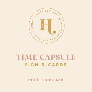 Może przedstawiać: Złote logo z literami "HJ" w środku koła. Koło ma napis "Hunny Prints Est. 2013" wokół niego. Pod logo znajduje się tekst "Time Capsule Sign & Cards" i "made to match".