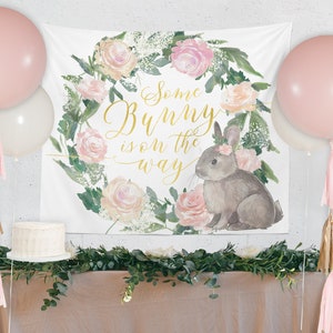 May include: A white banner with a floral wreath and a bunny rabbit. The banner says "Some Bunny is on the way".