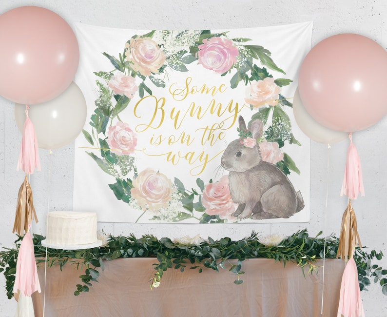 May include: A white banner with a floral wreath and a bunny rabbit. The banner says "Some Bunny is on the way".