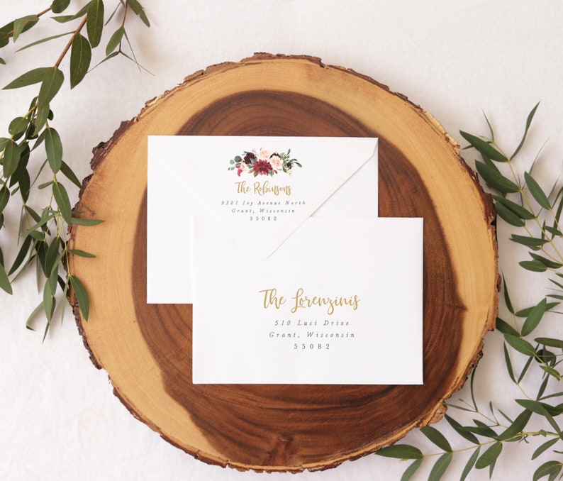 May include: Two white envelopes with gold calligraphy and floral designs. The top envelope has the text "The Refusjons" and the address "9301 109 Avenue North, Grant, Wisconsin 55082". The bottom envelope has the text "The Lorenzinis" and the address "510 Luci Drive, Grant, Wisconsin 55082".
