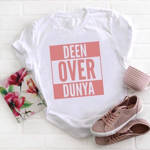 May include: White t-shirt with a pink square graphic that says "DEEN OVER DUNYA" in white letters.