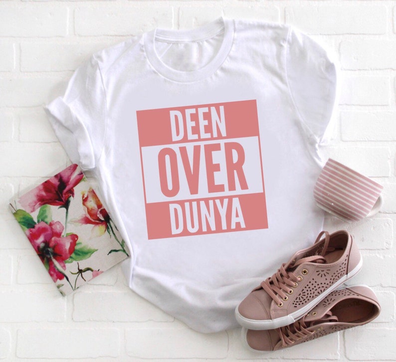 May include: White t-shirt with a pink square graphic that says "DEEN OVER DUNYA" in white letters.