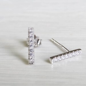 May include: A pair of silver bar earrings with clear cubic zirconia stones.