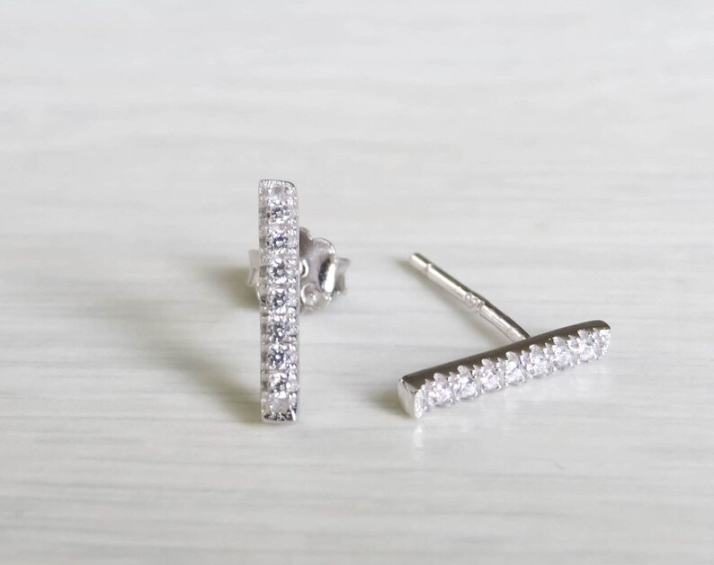 May include: A pair of silver bar earrings with clear cubic zirconia stones.
