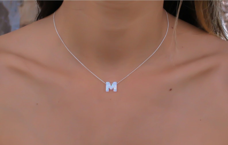 May include: A silver chain necklace with a white letter M pendant.