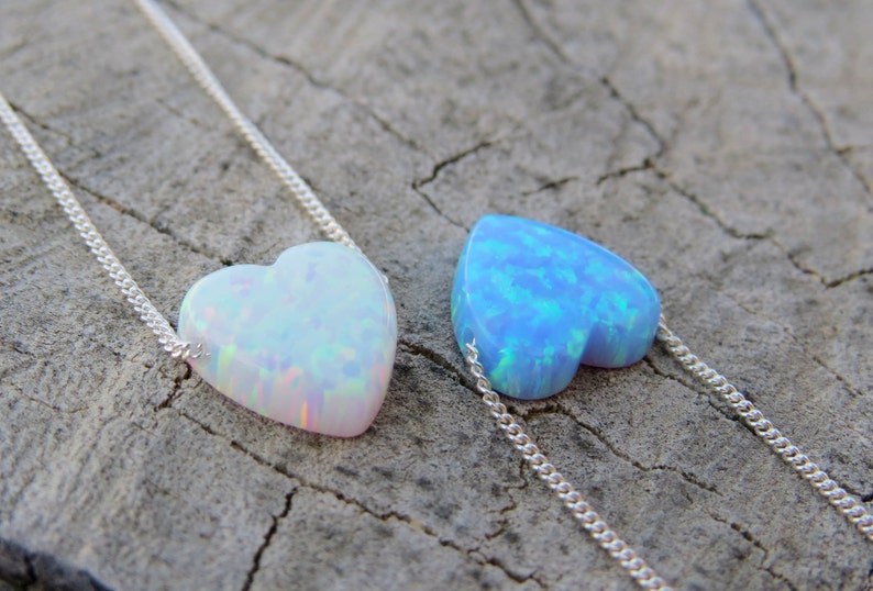 May include: Two silver necklaces with heart-shaped opal pendants. One pendant is white opal and the other is blue opal.