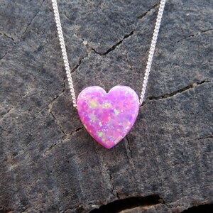May include: A silver chain necklace with a pink heart-shaped opal pendant.