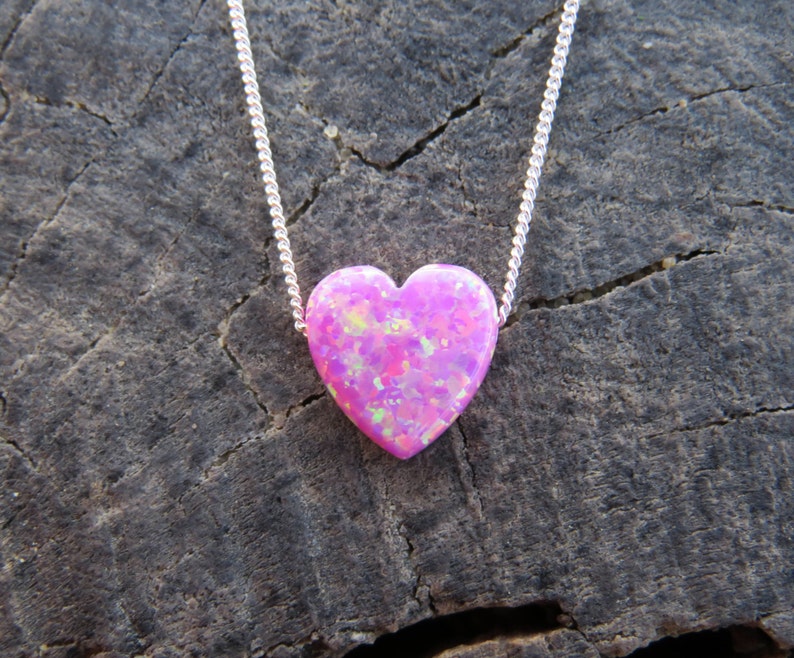 May include: A silver chain necklace with a pink heart-shaped opal pendant.