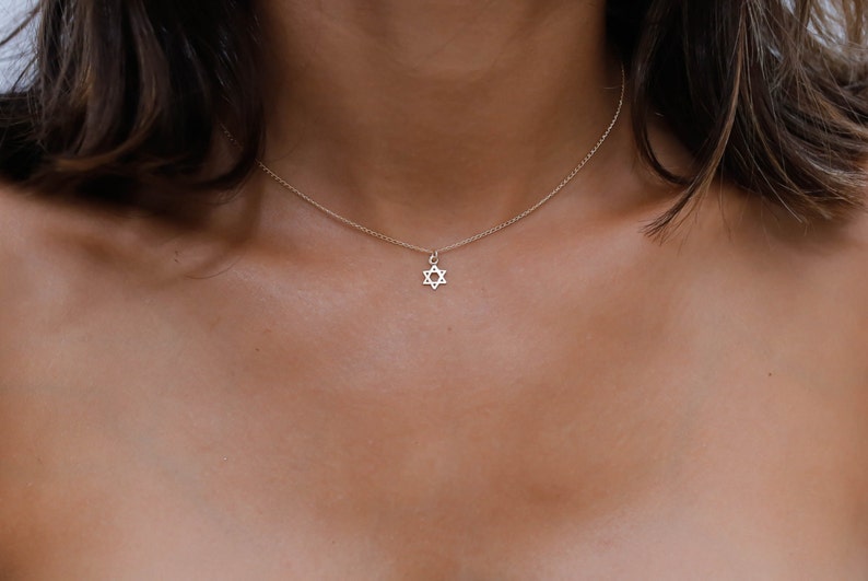 May include: A delicate gold chain necklace with a small, silver Star of David pendant.