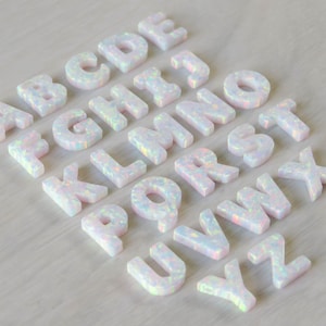 May include: White opal alphabet letter charms, A through Z, with iridescent sparkle. Each letter is individually crafted and features a unique, natural opal pattern.
