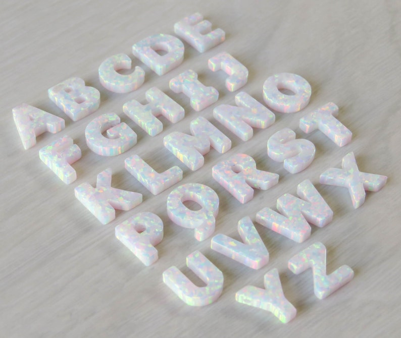 May include: White opal alphabet letter charms, A through Z, with iridescent sparkle. Each letter is individually crafted and features a unique, natural opal pattern.