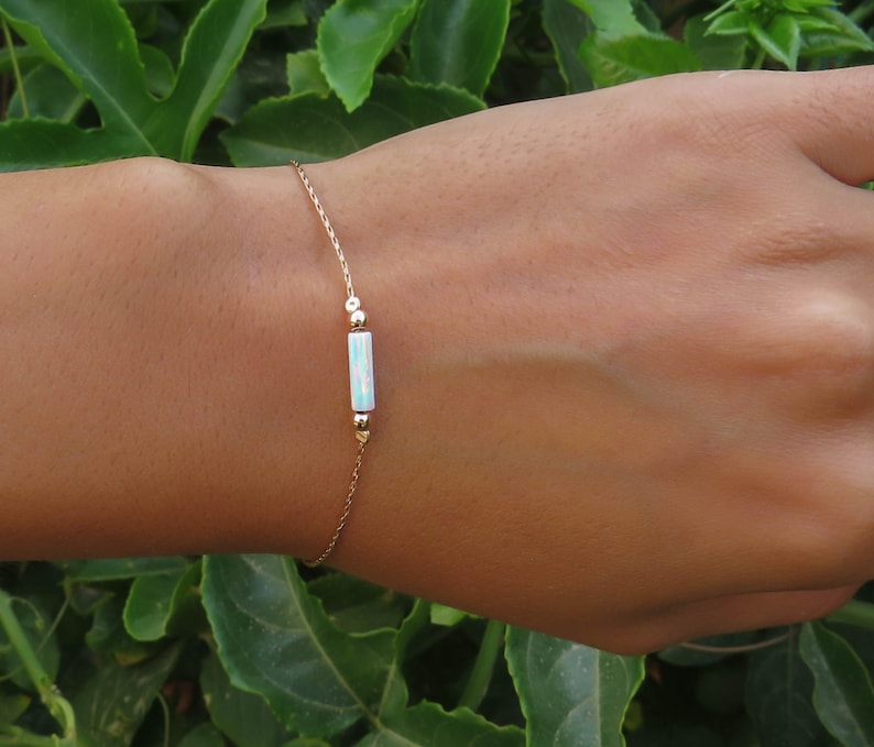 May include: A delicate gold chain bracelet with a single iridescent opal bar charm.
