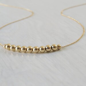 May include: A gold necklace with a row of small, round beads.
