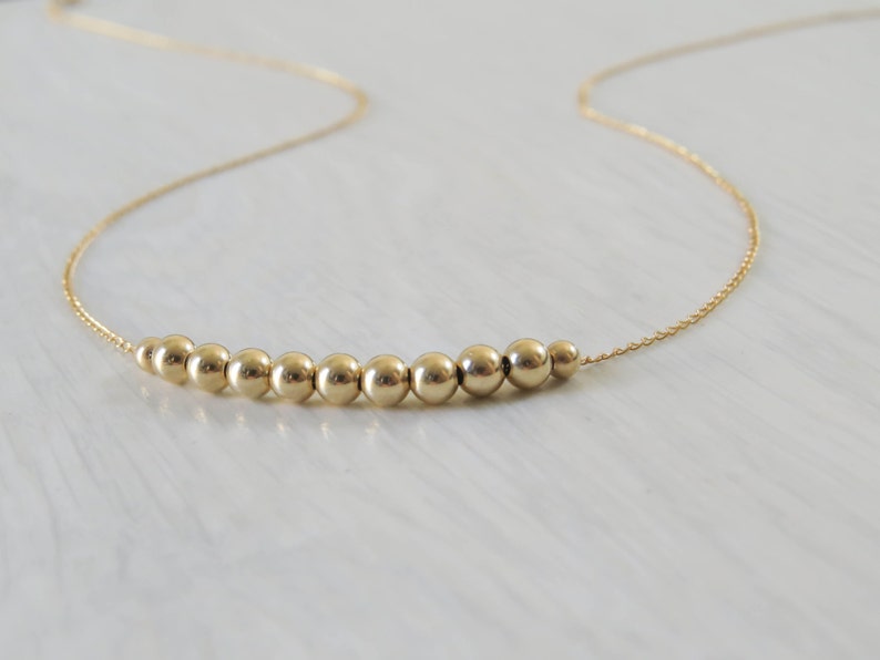 May include: A gold necklace with a row of small, round beads.