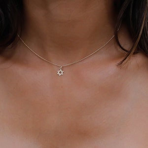 May include: A delicate silver chain necklace with a small, star of David pendant.