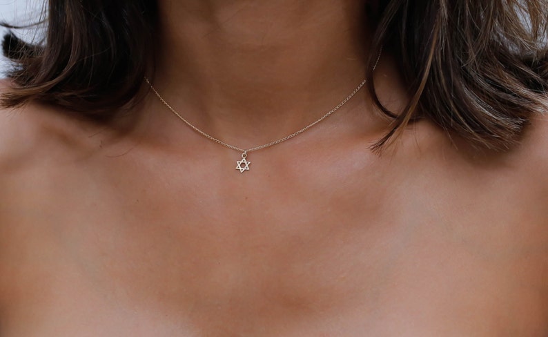 May include: A delicate silver chain necklace with a small, star of David pendant.