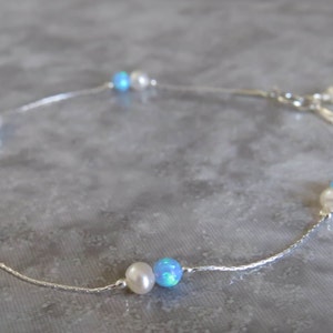 Pu&ograve; includere: Un braccialetto per caviglia in catena d'argento con perle bianche e perle di opale blu alternate.
