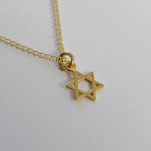 May include: A gold chain necklace with a small, delicate gold Star of David pendant.
