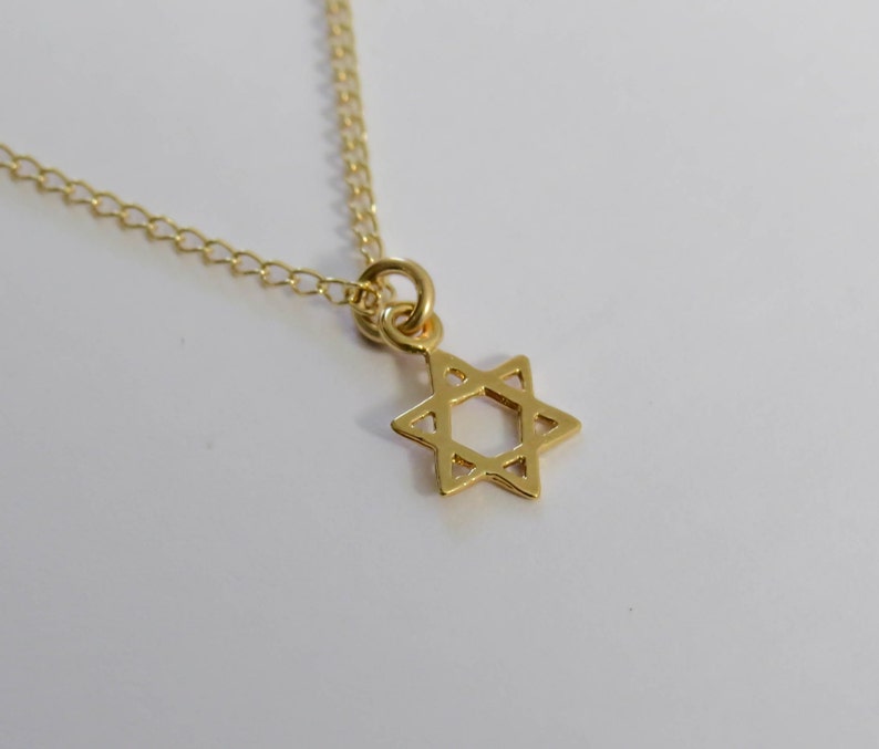 May include: A gold chain necklace with a small, delicate gold Star of David pendant.