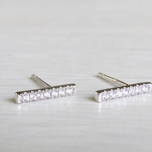 May include: A pair of silver bar stud earrings with clear cubic zirconia stones.