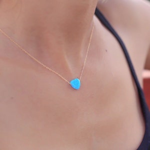 May include: A delicate gold chain necklace with a small, light blue teardrop-shaped pendant.