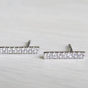 May include: A pair of silver bar earrings with small clear cubic zirconia stones.