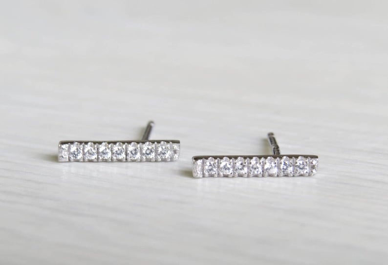 May include: A pair of silver bar earrings with small clear cubic zirconia stones.