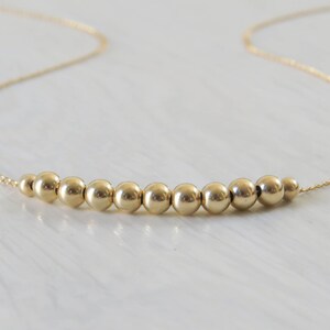 May include: A gold necklace with a row of small, round beads.