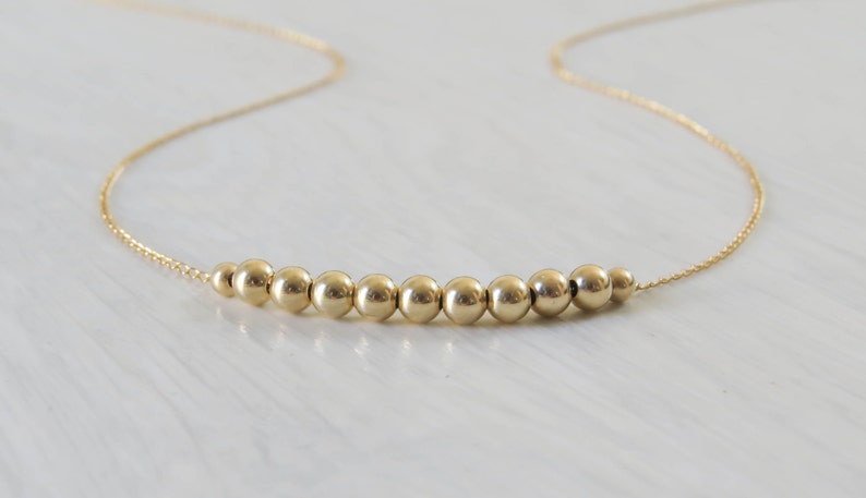 May include: A gold necklace with a row of small, round beads.