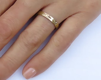 May include: A thin gold band ring with a delicate floral design.