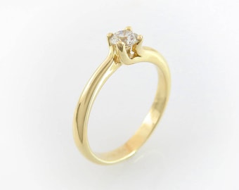 May include: A simple gold band engagement ring with a single round diamond.