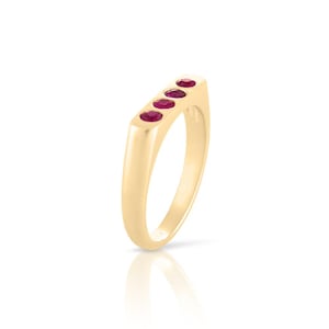 Può includere: Un anello d'oro con cinque pietre preziose rosse incastonate in una fascia rettangolare.