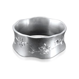 Puede incluir: Un anillo de plata con una banda ondulada y un dise&ntilde;o floral grabado. Las flores son estilizadas y tienen cinco p&eacute;talos.