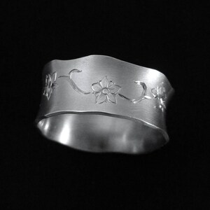 Puede incluir: Un anillo de plata con un dise&ntilde;o floral. El anillo est&aacute; hecho de metal y tiene un acabado liso y pulido.