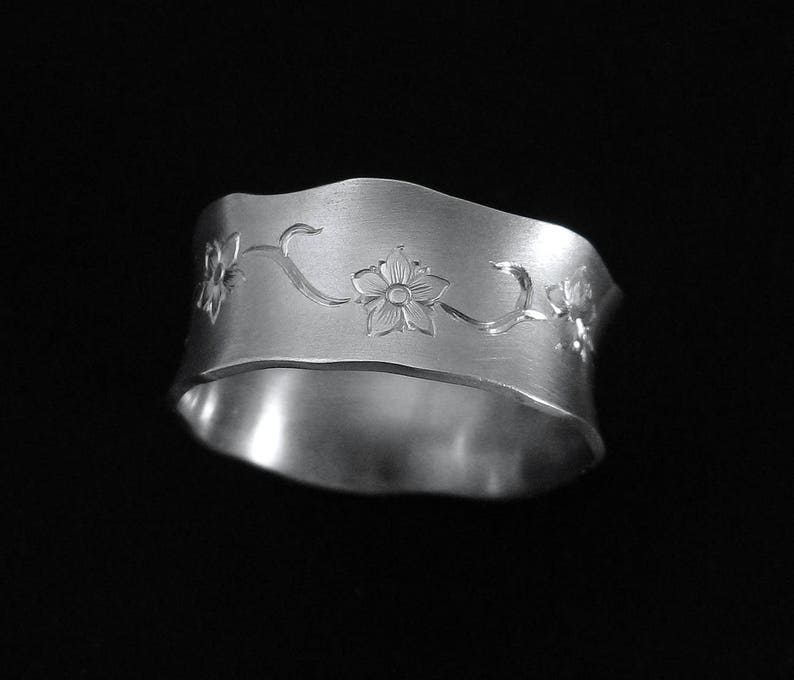 Puede incluir: Un anillo de plata con un dise&ntilde;o floral. El anillo est&aacute; hecho de metal y tiene un acabado liso y pulido.