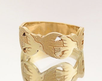 May include: A gold band ring with a design of three doves in flight. The doves are intricately carved and have a textured finish.