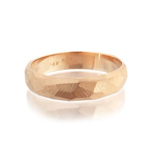 May include: A 14k gold band ring with a textured, faceted finish. The ring is a simple, classic design.