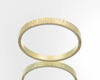 May include: A simple gold band ring with a textured surface.