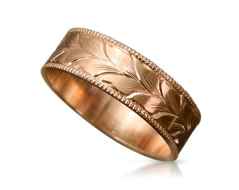 Puede incluir: Un anillo de banda de oro rosa con un patrón de hojas grabado alrededor de la banda.