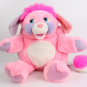 May include: A plush pink stuffed animal with a pink mohawk, purple accents, and blue eyes. The toy has large ears, a white belly, and a detached pink and white tuft of fur. A vintage collectible.