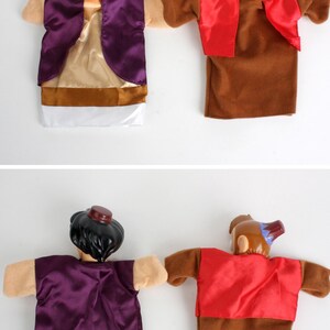 Puede incluir: Dos marionetas de mano con personajes de una popular pel&iacute;cula de animaci&oacute;n. Una marioneta es un personaje con cabello negro, que lleva un chaleco morado y una camisa beige. La otra es un mono marr&oacute;n con un chaleco rojo.