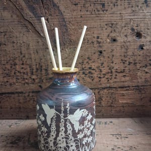 May include: A white ceramic mug with a black handle and the text "But First, Coffee" in a black, handwritten-style font. The mug is on a white surface.