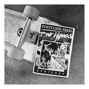 May include: Black and white photo of a skateboard with a flyer on top. The flyer is for a Tony Hawk's Pro Skater event in Brisbane, Australia. The flyer says "Postcode Press" and "Birdhouse".
