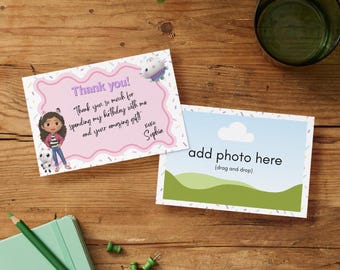 Peut inclure: Deux cartes de vœux sur une surface en bois. L'une a une bordure rose avec le texte "Thank you!" et un message manuscrit. L'autre a un ciel bleu et un paysage vert avec le texte "add photo here".