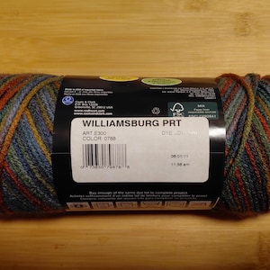 May include: A skein of Williamsburg PRT yarn in color 0788. The yarn is a mix of blue, green, orange, and yellow. The label includes the text "WILLIAMSBURG PRT", "ART E300", and a barcode.
