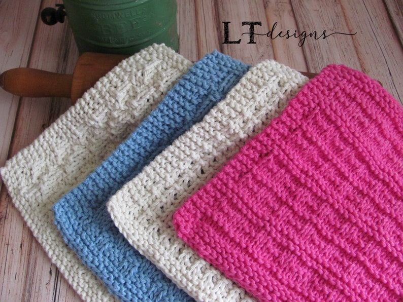 May include: Four knitted dishcloths in different colors and patterns. The dishcloths are stacked on top of each other. The top dishcloth is pink, the next is white, the next is blue, and the bottom dishcloth is white.