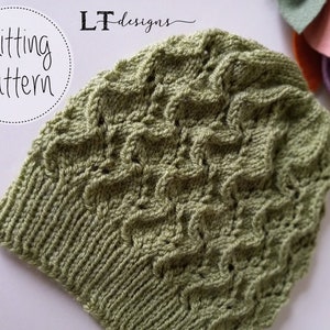 May include: A green knitted hat with a textured pattern. The hat is made with a stitch that creates a wave-like effect. The hat is shown on a white background.