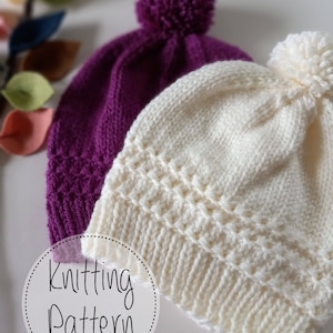 May include: Two knitted hats with pom poms. One hat is purple and the other is white. The hats are on a white background with the text "Knitting Pattern" in a circle.