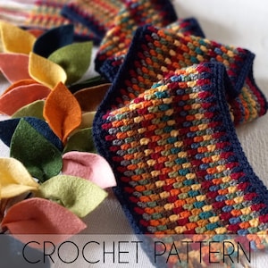 May include: A crochet pattern for a colorful scarf with a navy blue border. The pattern is called "LT designs".