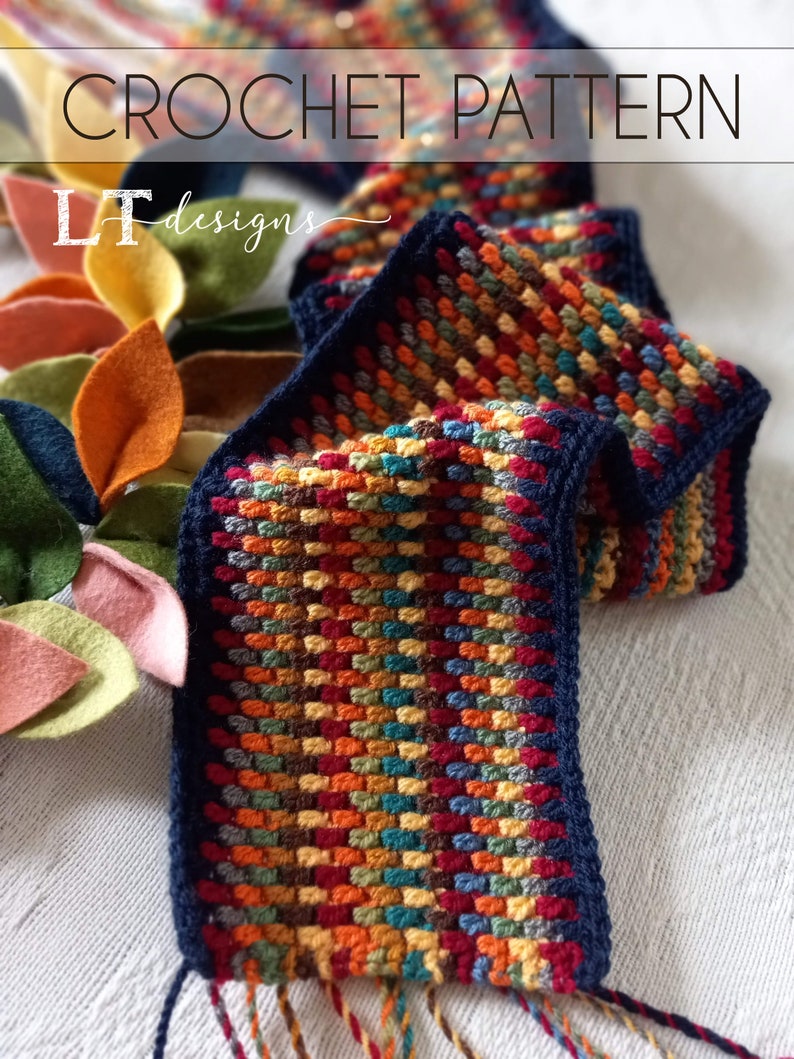 May include: A colorful crochet scarf with a navy blue border and fringe. The scarf is made with a variety of colors, including red, orange, yellow, green, blue, and brown. The scarf is crocheted in a textured stitch.